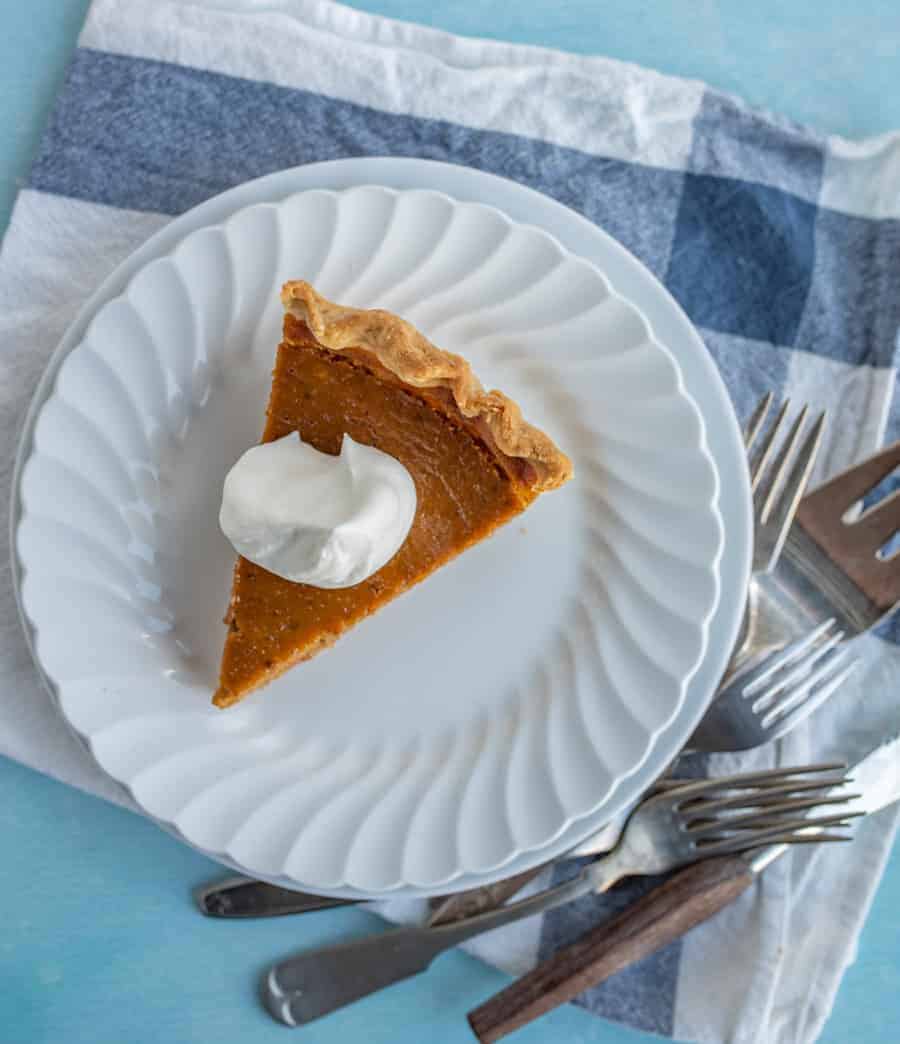 An overhead shot of a piece of pumpkin pie with a dollop of whipping cream on top.