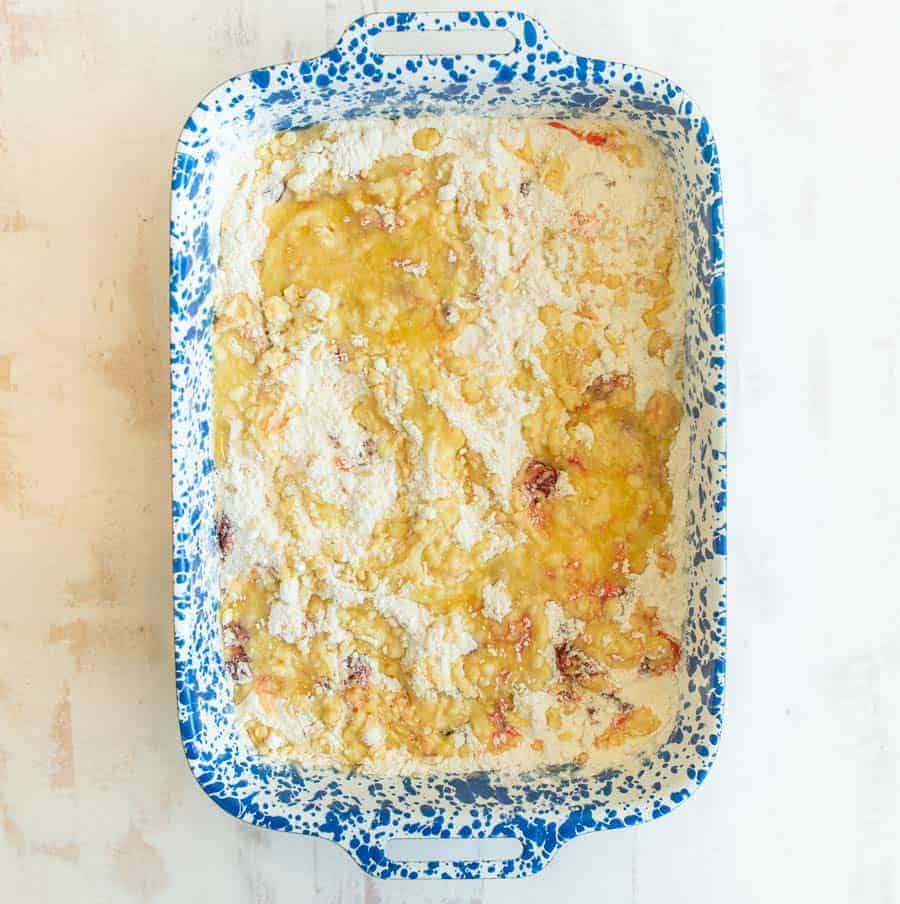 Overhead shot of a blue and white speckled rectangular pan filled with the ingredients to make a cherry dump cake.