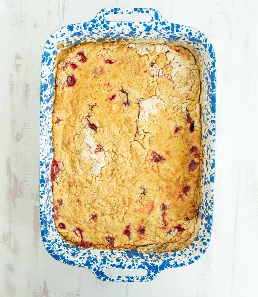 Overhead shot of a cooked cherry dump cake in a blue and white speckled rectangular pan.