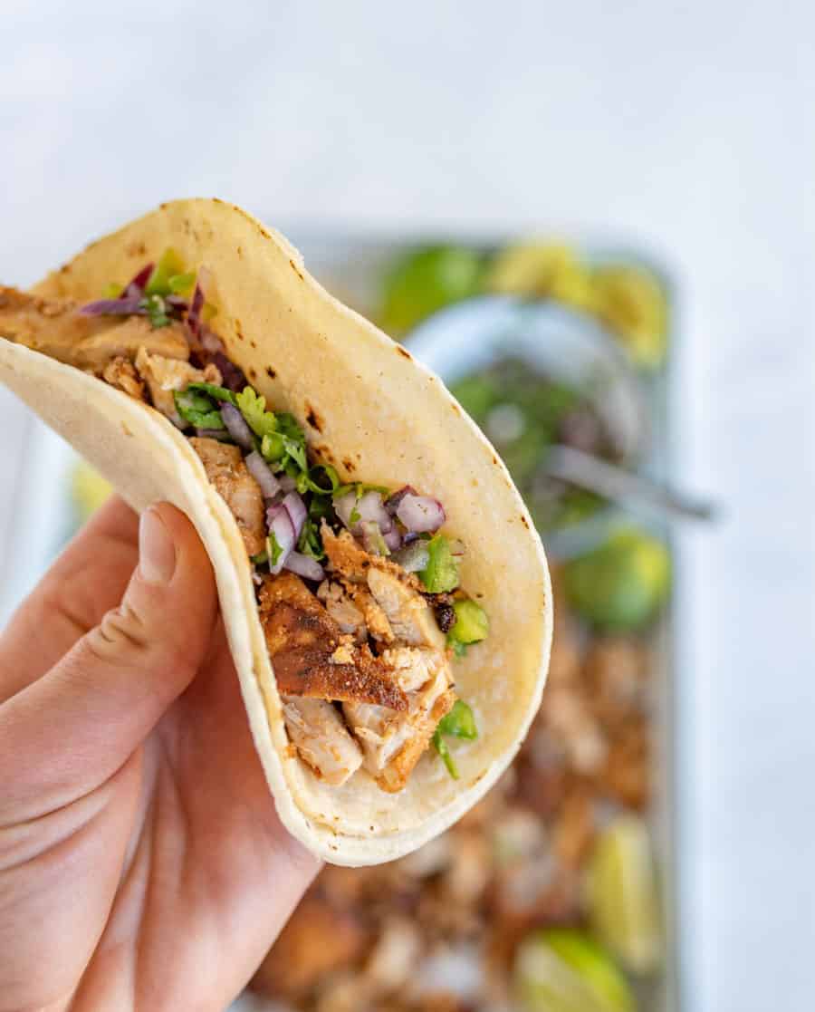 woman holding chicken taco made with two tortillas