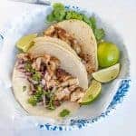 two chicken tacos on a white and blue plate