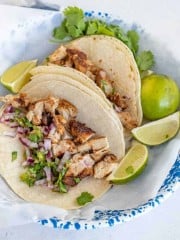 two chicken tacos on a white and blue plate