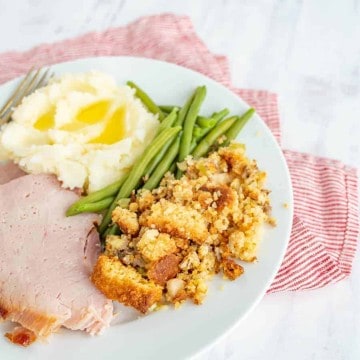 ham mashed potatoes green beans and stuffing on a white plate