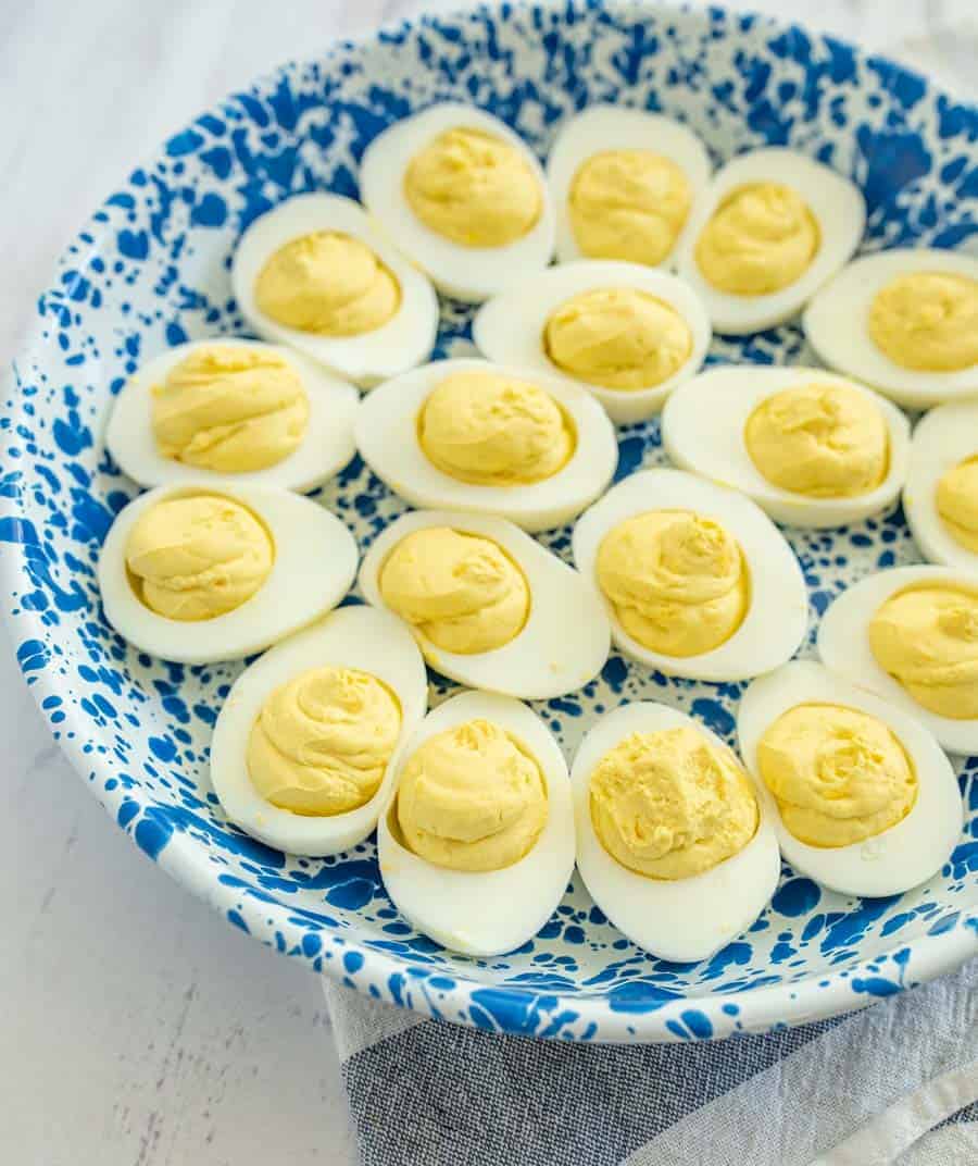 closeup deviled eggs in blue and white bowl on white countertop