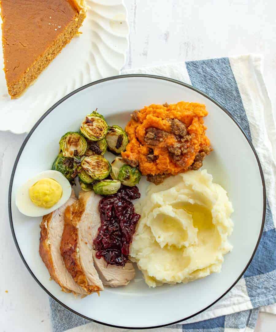 Thanksgiving dinner plate with mashed potatoes deviled egg brussels sprouts sweet potato casserole mashed potatoes turkey and cranberry sauce