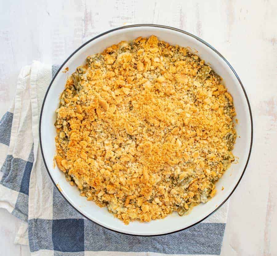 Green bean casserole in white baking dish on blue and white towel