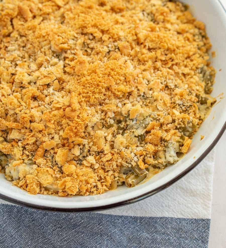 closeup of green bean casserole in round white casserole dish on blue and white towel