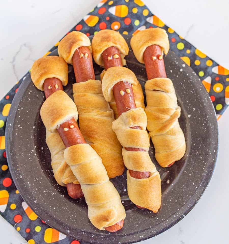 Halloween mummy hot dogs are the cutest little festive snacks (reminiscent of pigs in a blanket) for a fun and creative Halloween party food! You'll be the talk of the Halloween party with these adorable mummy hot dogs, and the best part is that they only take 3 ingredients and a few minutes to make! #mummydogs #mummyhotdogs #crescentdogs #crescentrolls #pigsinablanket #halloweenrecipes #halloweensnacks