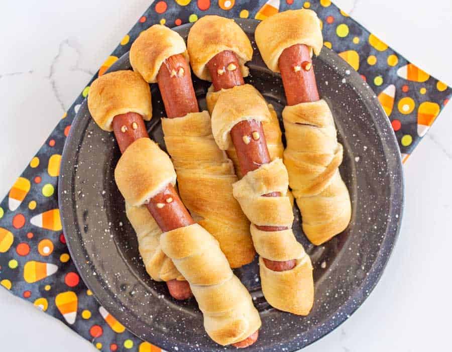 Halloween mummy hot dogs are the cutest little festive snacks (reminiscent of pigs in a blanket) for a fun and creative Halloween party food! You'll be the talk of the Halloween party with these adorable mummy hot dogs, and the best part is that they only take 3 ingredients and a few minutes to make! #mummydogs #mummyhotdogs #crescentdogs #crescentrolls #pigsinablanket #halloweenrecipes #halloweensnacks