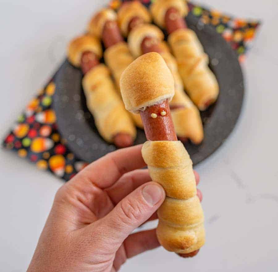 Halloween mummy hot dogs are the cutest little festive snacks (reminiscent of pigs in a blanket) for a fun and creative Halloween party food! You'll be the talk of the Halloween party with these adorable mummy hot dogs, and the best part is that they only take 3 ingredients and a few minutes to make! #mummydogs #mummyhotdogs #crescentdogs #crescentrolls #pigsinablanket #halloweenrecipes #halloweensnacks