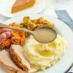 spoon dripping gravy on top of mashed potatoes