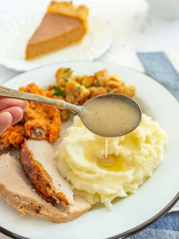 spoon dripping gravy on top of mashed potatoes