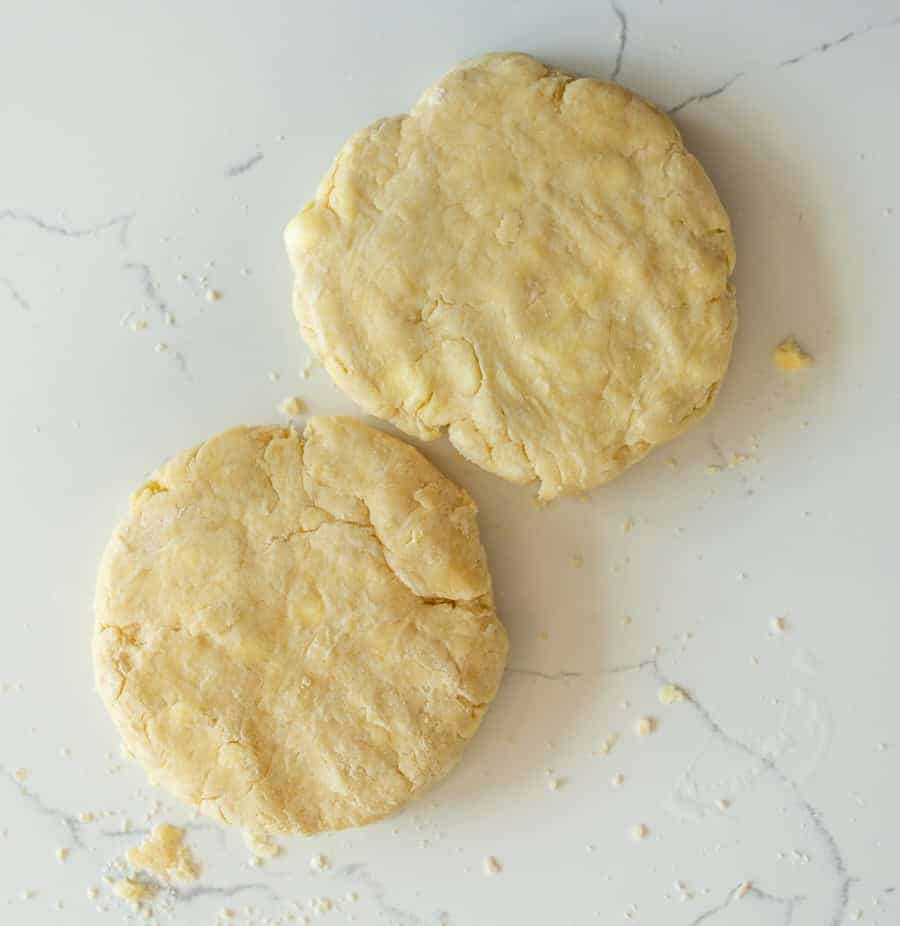 two pieces of pie dough before being rolled out on a marble countertop