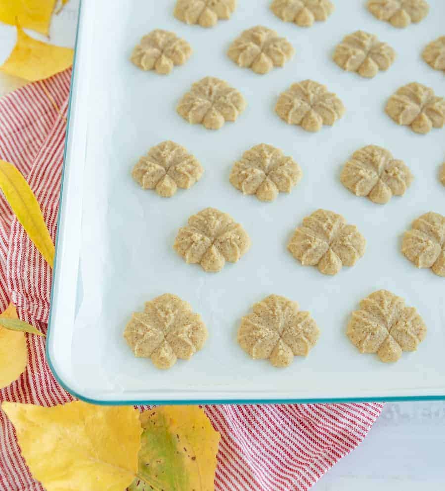Upclose picture of spritz cookies on a white baking sheet.