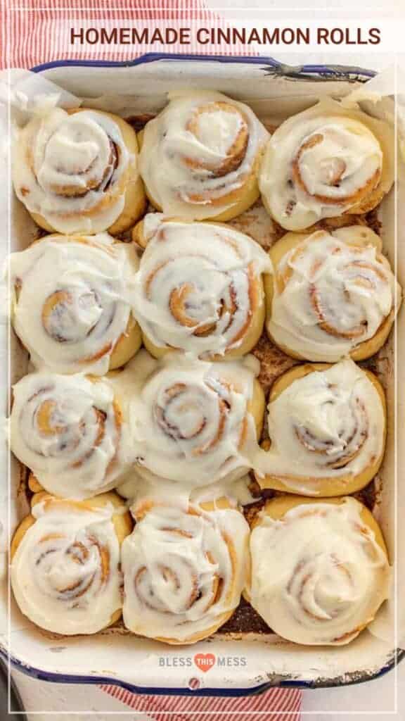 A baking dish with a dozen cinnamon rolls with frosting