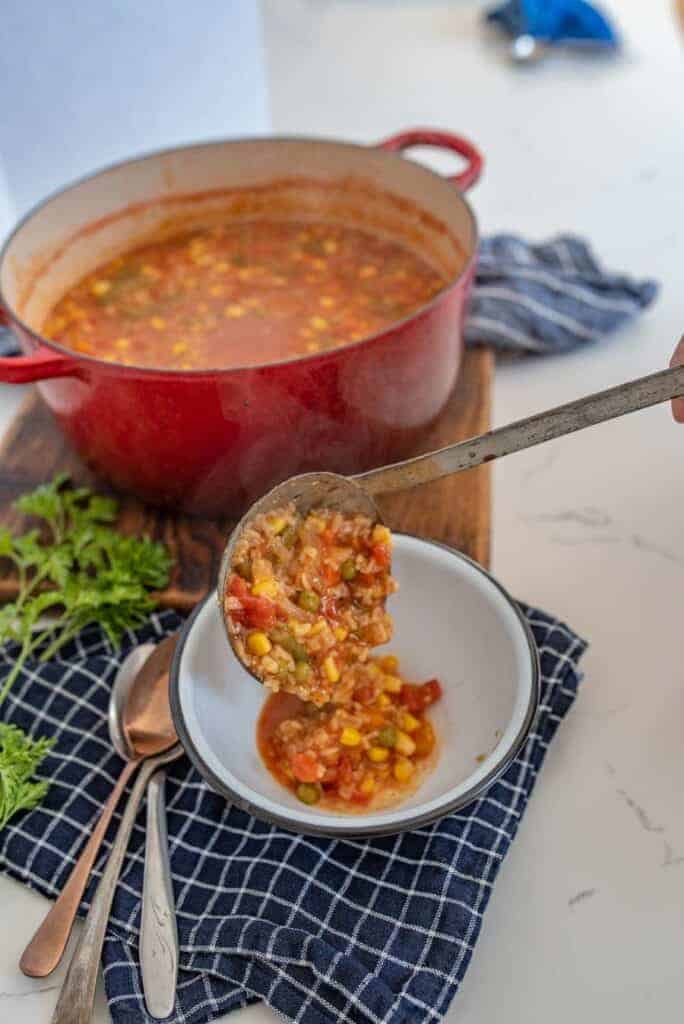 ladle scooping out alphabet soup from a crock pot