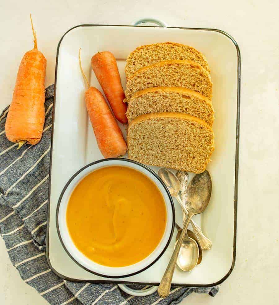 tray with bowl of carrot soup and homemade bread