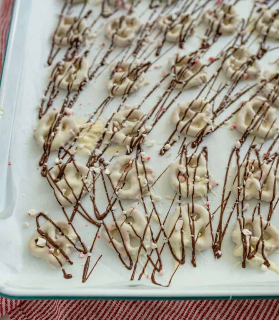 sheet pan of pretzels with white chocolate drizzled with milk chocolate and sprinkled with broken candy canes