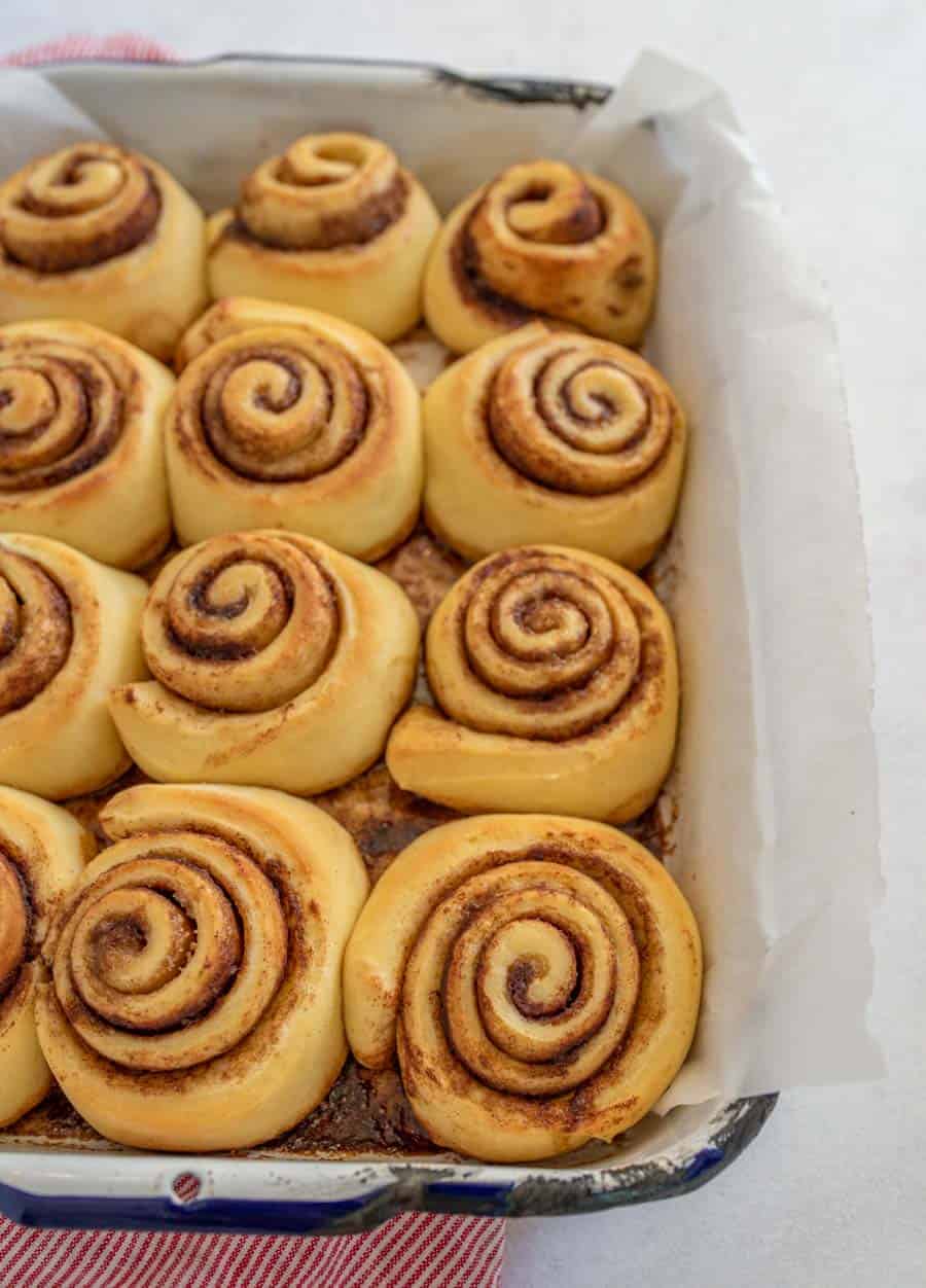 An overhead view of almost a full pan of cooked cinnamon rolls.