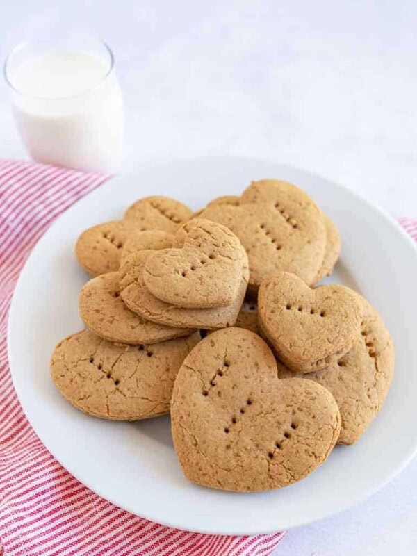 graham crackers in the shape of little hearts with fork punctures in them on a stack on a plate