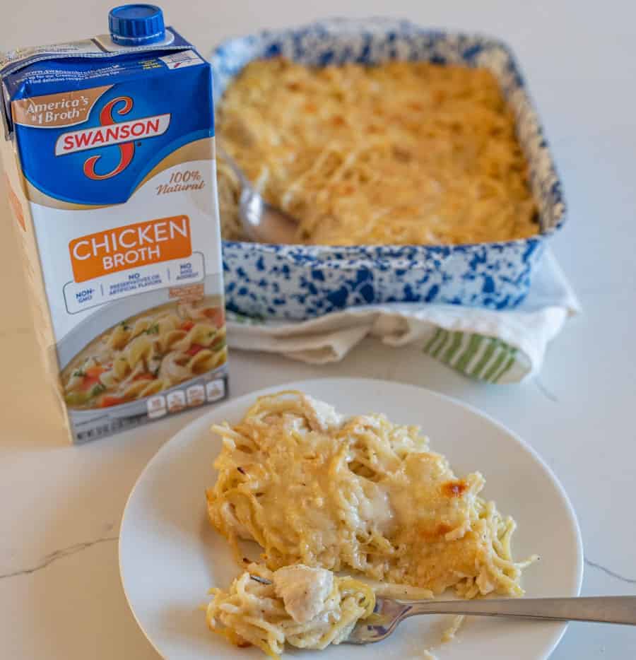 creamy turkey tetrazzini like a casserole in a dish next to a box of chicken broth
