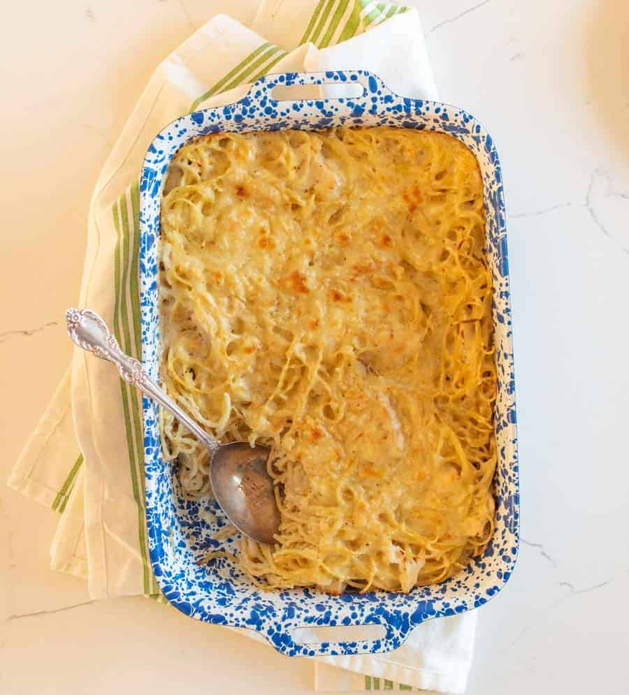 A blue and white rectangular baking dish filled with cheesy turkey tetrazzini pasta bake