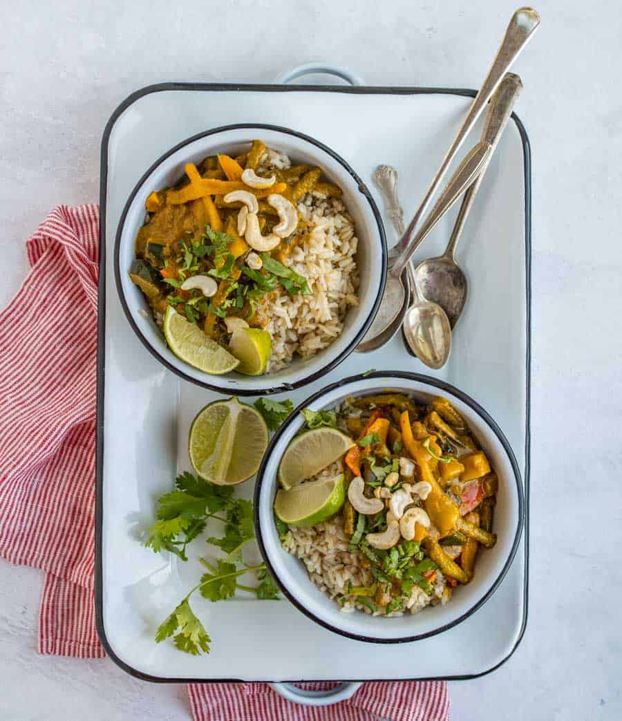 two bowls of easy vegetable curry on white serving tray with spoons