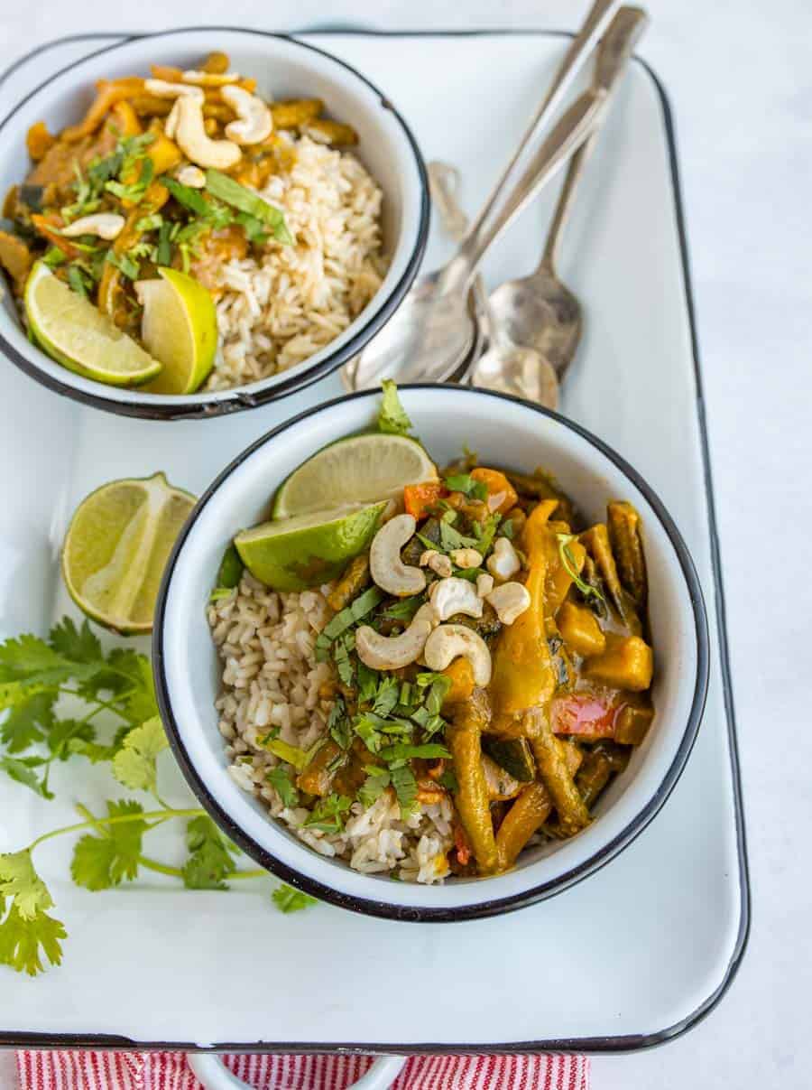 two bowls of easy vegetable curry on white serving dish with spoons