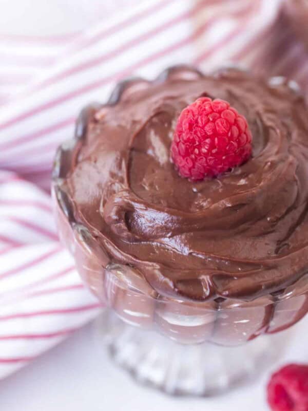 top view of chocolate pudding in a glass parfait dish with a raspberry on top