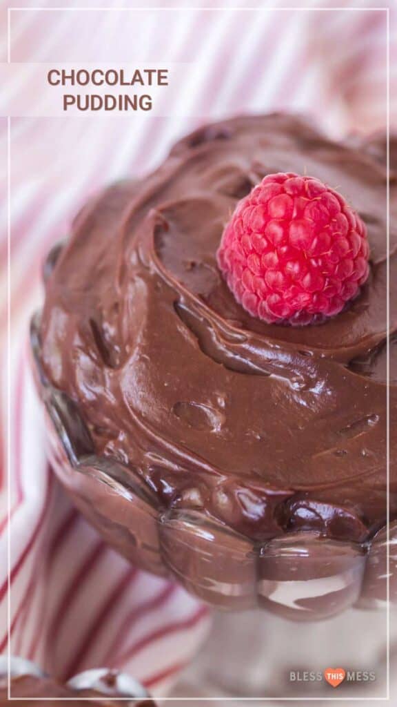 chocolate pudding with a raspberry on top in a clear glass parfait dish