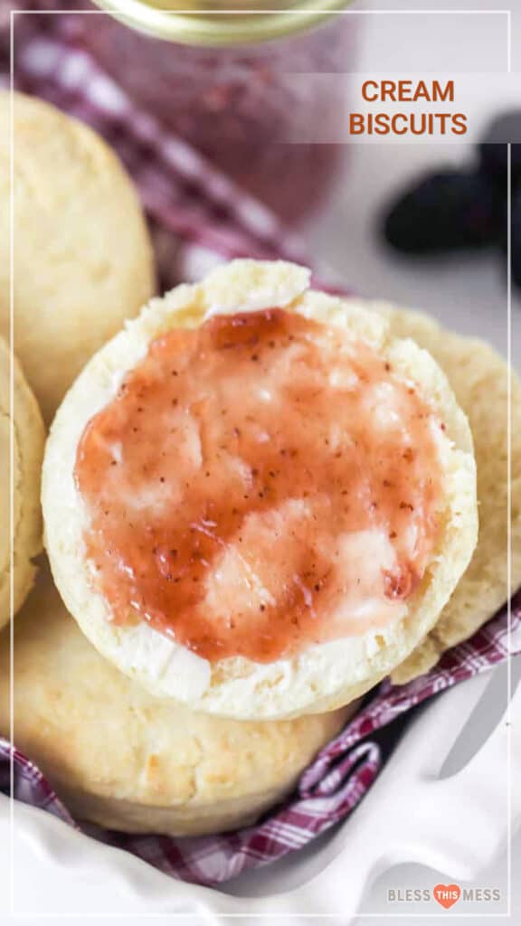 cream biscuit with jelly on red and white towel in white dish.