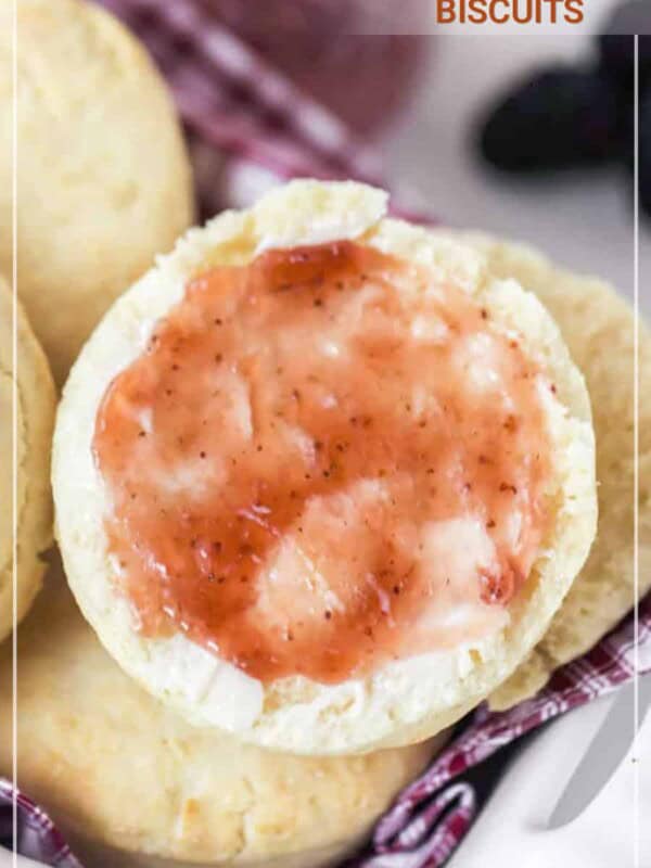 cream biscuit with jelly on red and white towel in white dish.