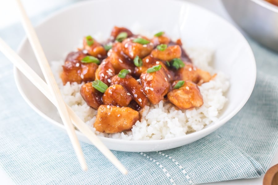 general tso's chicken with white rice in white bowl with chopsticks