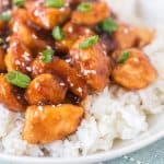 sticky general tso's chicken pieces over rice in a white bowl up close