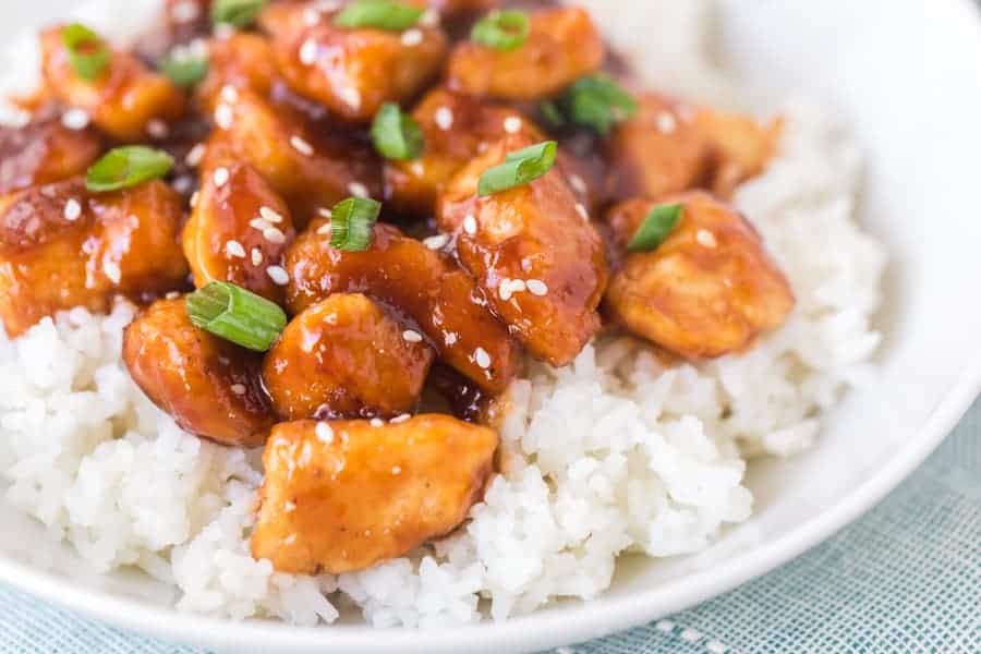 General Tso's Chicken with White Rice in white bowl on blue towel