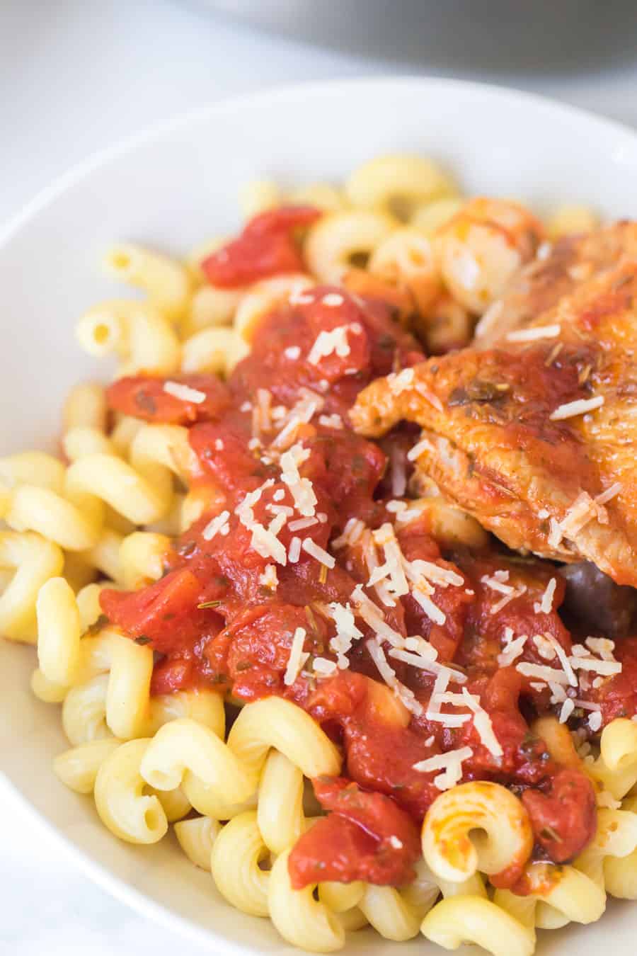 tomato and garlic pasta with chicken thigh in white bowl
