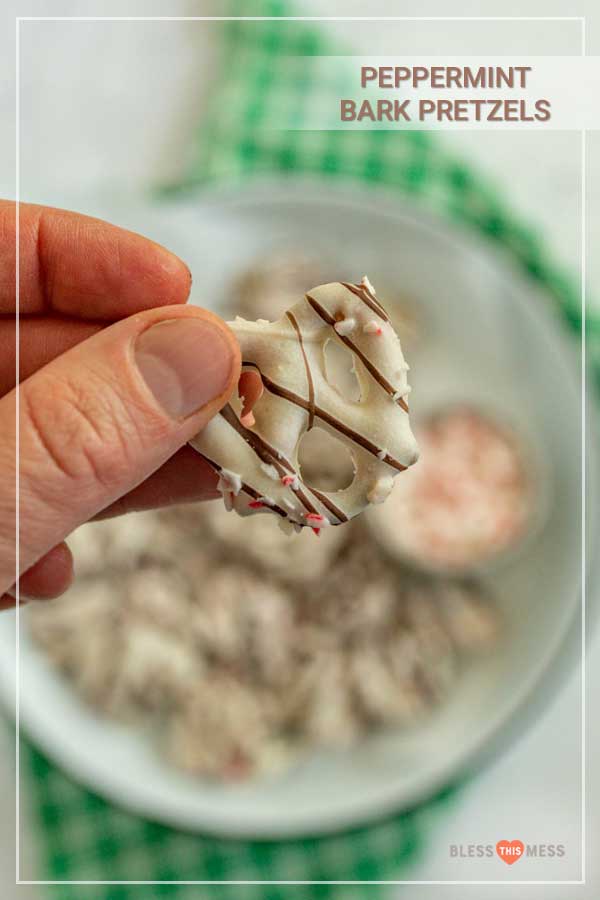 hang holding a white chocolate dipped pretzel with broken candy cane mint bits and chocolate drizzle