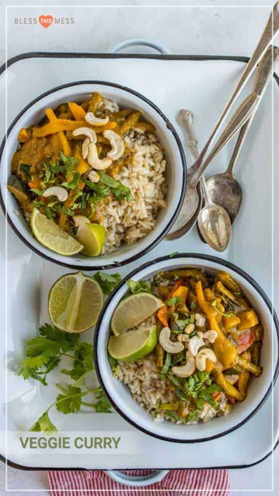 two bowls of easy vegetable curry on white serving tray with spoons