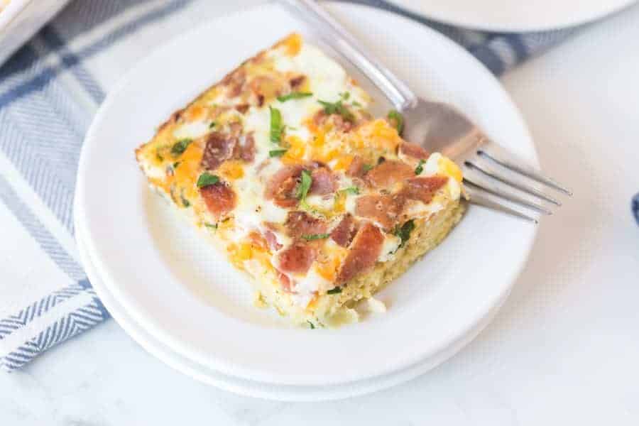 a square of egg bake like quiche without the crust on a white plate with a fork