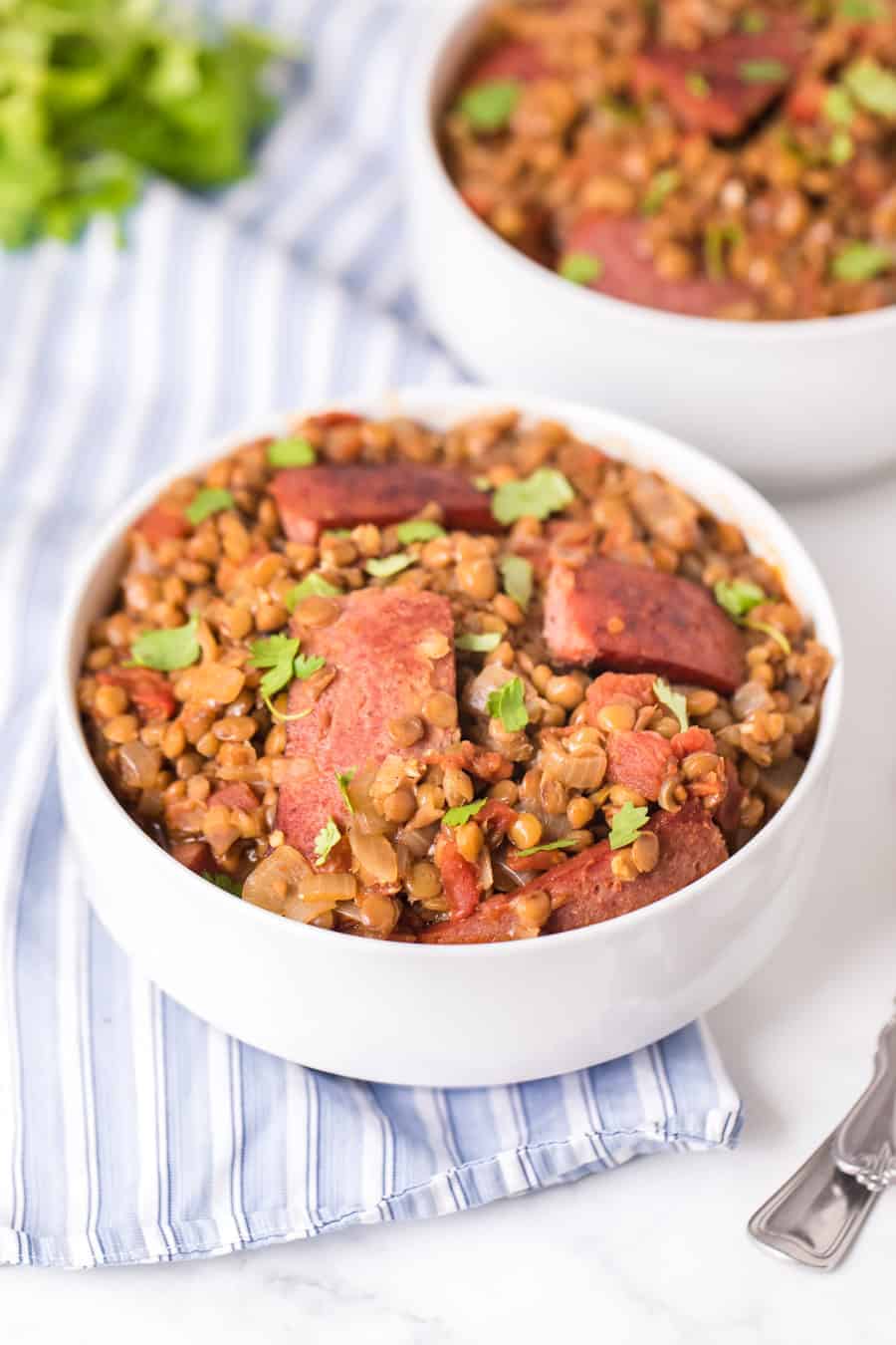 two white bowls of Spicy Lentils with Sausage