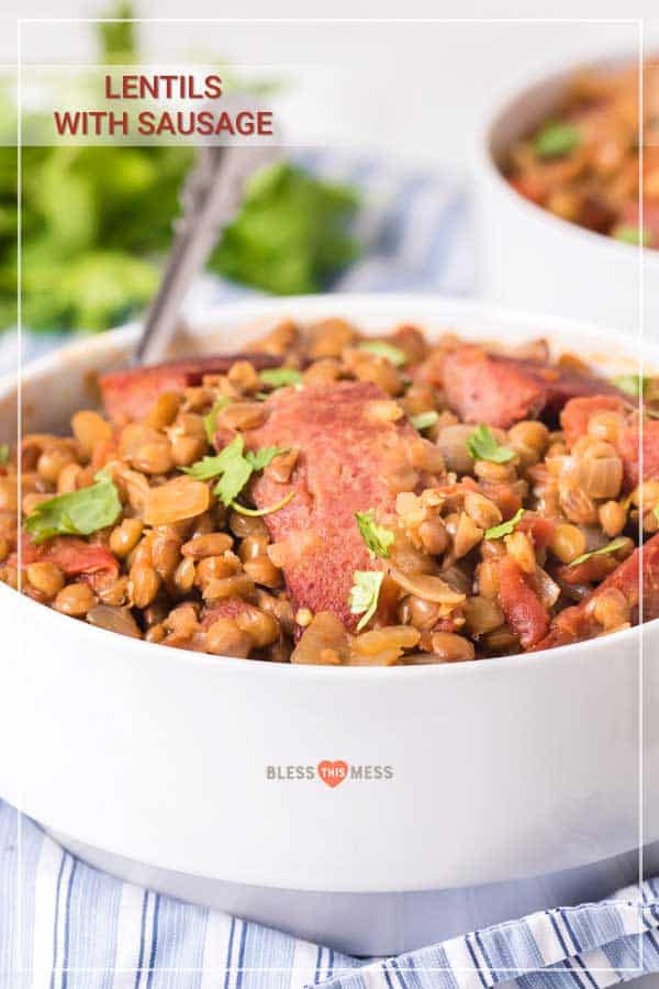 spicy lentils and sausage in white bowl with fork