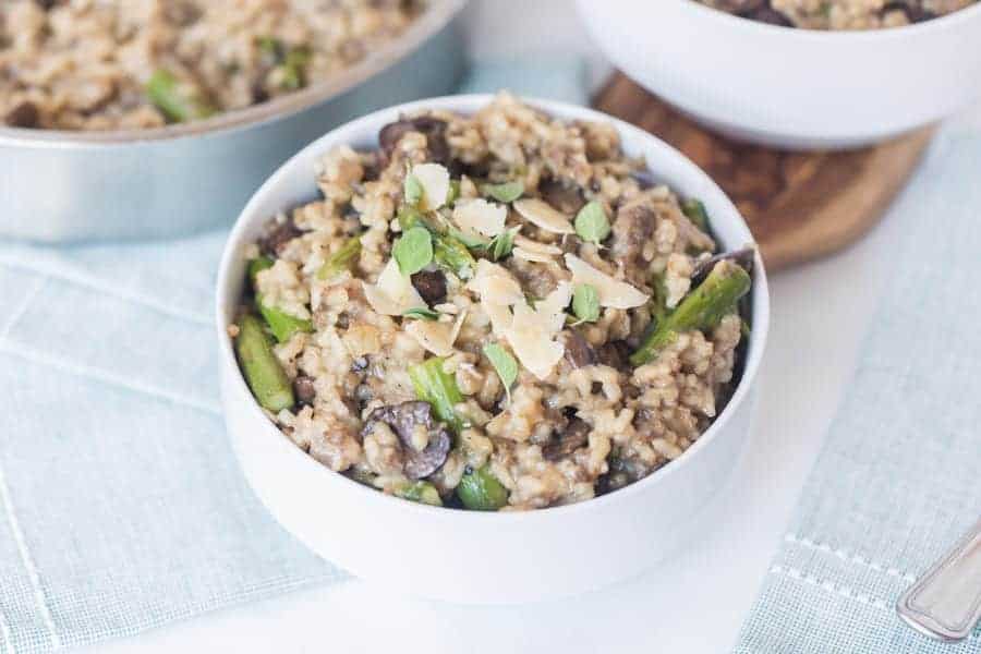 close up - mushroom and asparagus risotto in a bowl garnished with cheese shavings