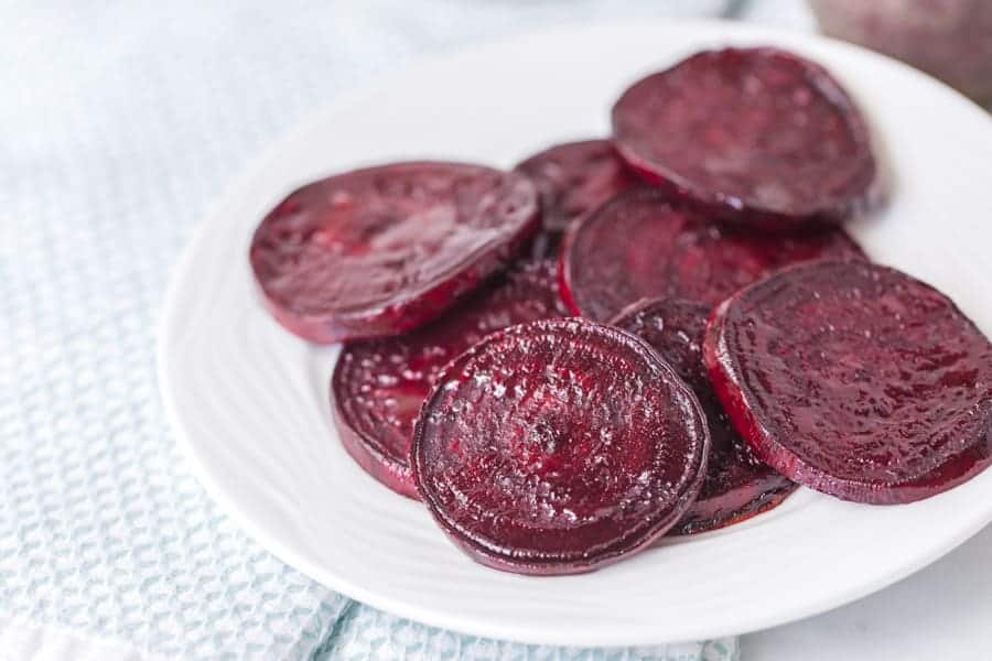 roasted beet slices on round white plate on white and light blue towel
