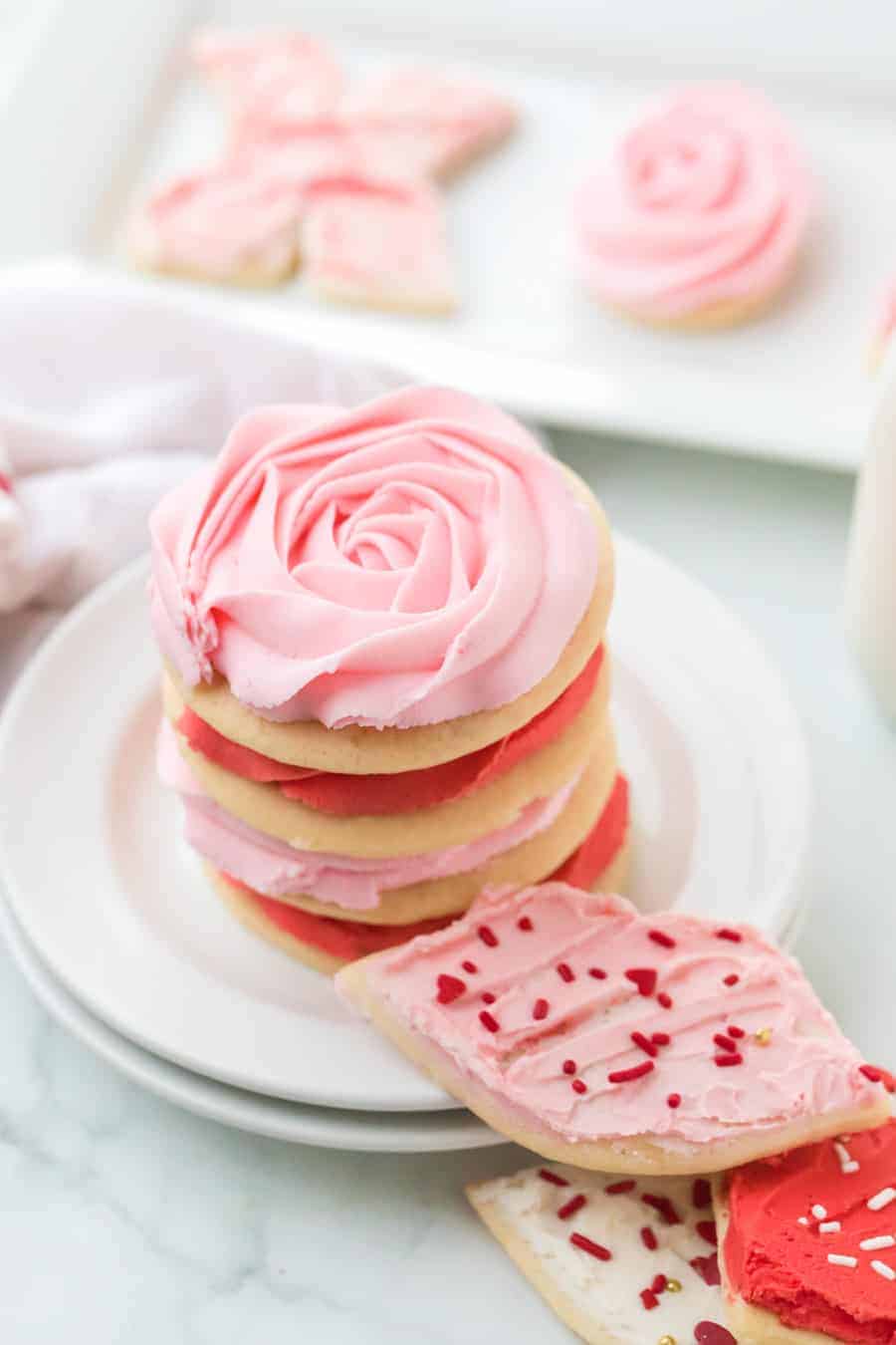 stack of iced valentine's sugar cookie cutouts on round white plates