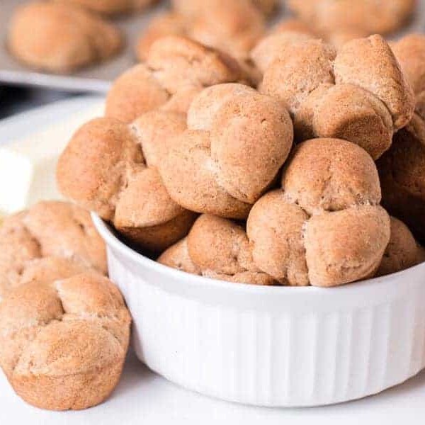 a pile of whole wheat clover rolls on a white ceramic bowl