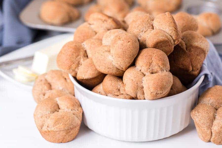 a pile of whole wheat clover rolls on a white ceramic bowl