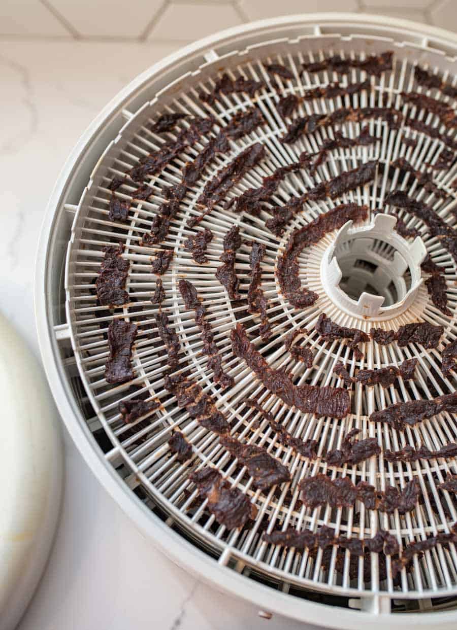 beef jerky on dehydrator sitting on white countertop