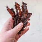 woman holding beef jerky strips closeup