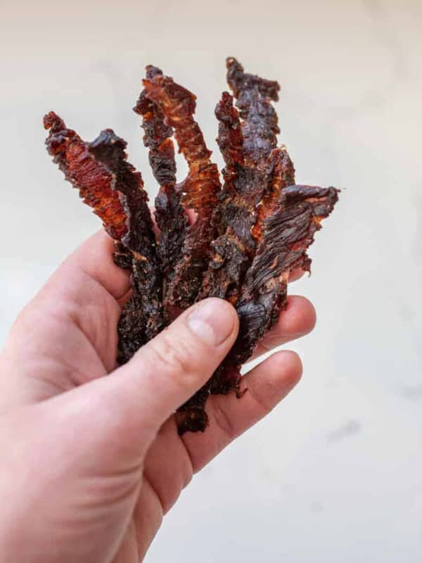 woman holding beef jerky strips closeup