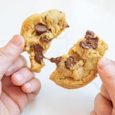 hands pulling apart a delicious chocolate chip cookie